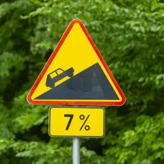 Znak ostrzegawczy: strome zbocze, nachylenie 7%. Jak elektroda dodatnia, która kieruje prąd w górę, tak i ten znak ostrzega przed stromym podjazdem.