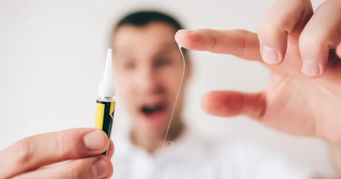 Zastanawiasz się, czym zmyć super glue z rąk? Oto mała nić, która przykleiła się do palca, obok tubki kleju.