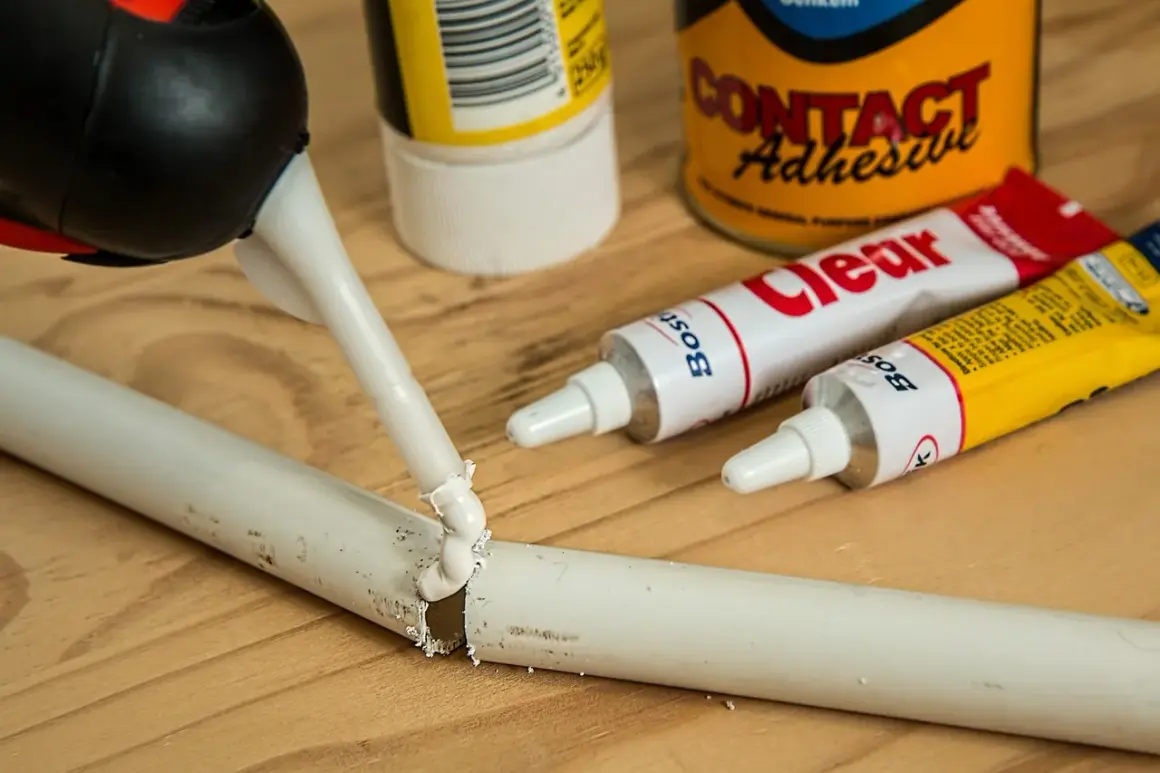Aplikator z klejem naprawia pękniętą rurkę. W tle tubki kleju "Clear" i "Contact Adhesive" – idealne, by dowiedzieć się, czym skleić plastik.