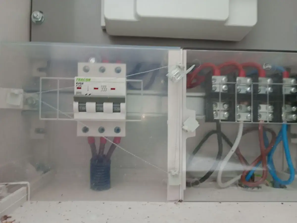 W skrzynce elektrycznej widać zabezpieczenie przedlicznikowe Tracon, przewody czerwone, niebieskie i brązowe.